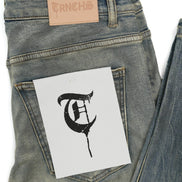 Denim jeans with a brand label and a black letter 'Q' on a white card.