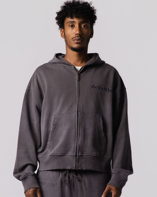 A man wearing a dark gray zip-up hoodie and matching sweatpants with 'setnile' printed on the chest, photographed against a solid light gray background.