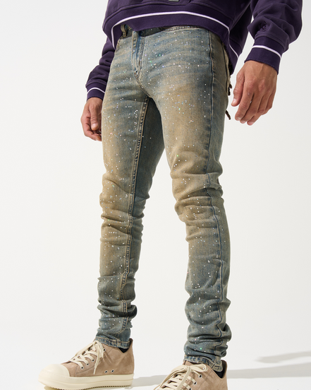 Person wearing distressed blue jeans and beige sneakers on a white background