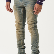 Person wearing blue jeans with white speckles and beige sneakers on a white background