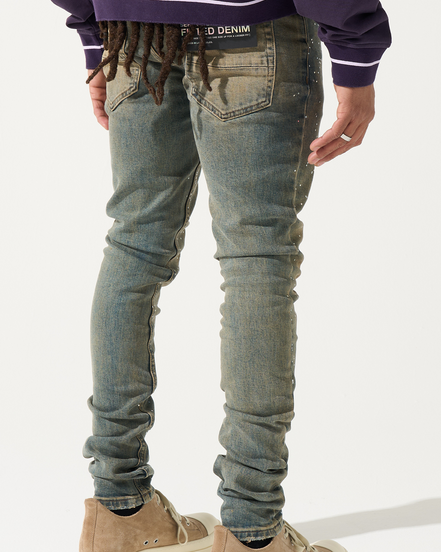 Person wearing distressed blue jeans and brown shoes on a white background