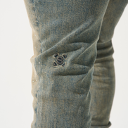 Close-up of a person wearing blue jeans with a brand logo on a white background