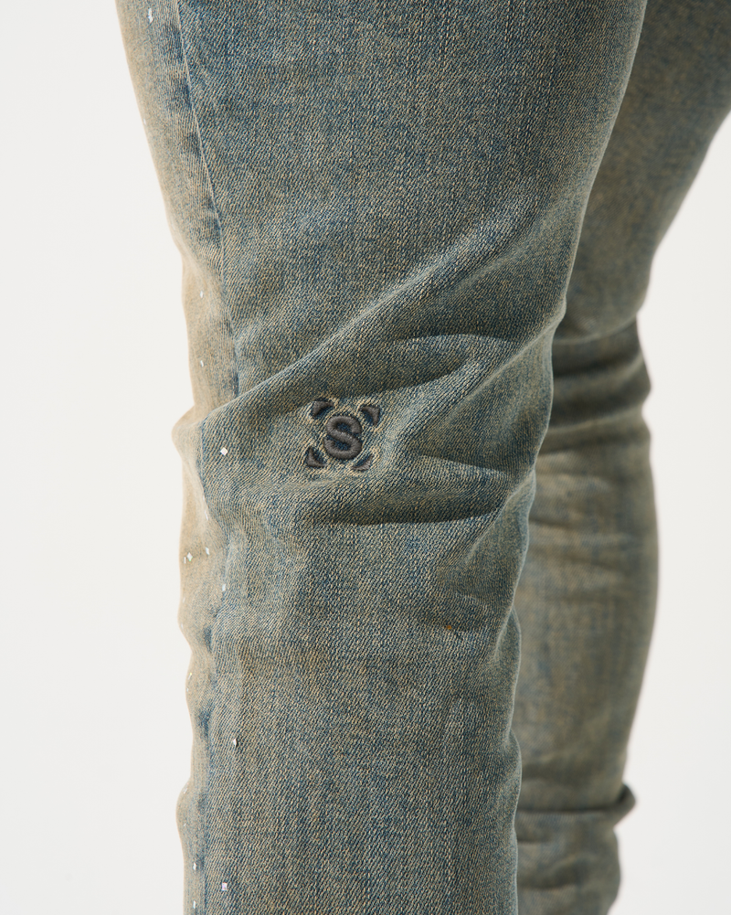 Close-up of a person wearing blue jeans with a brand logo on a white background