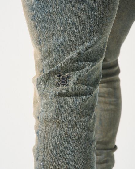 Close-up of a person wearing blue jeans with a brand logo on a white background