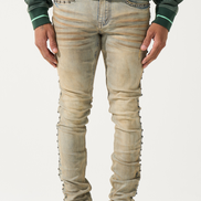 Person wearing beige distressed jeans with a green sweater and maroon sneakers on a white background