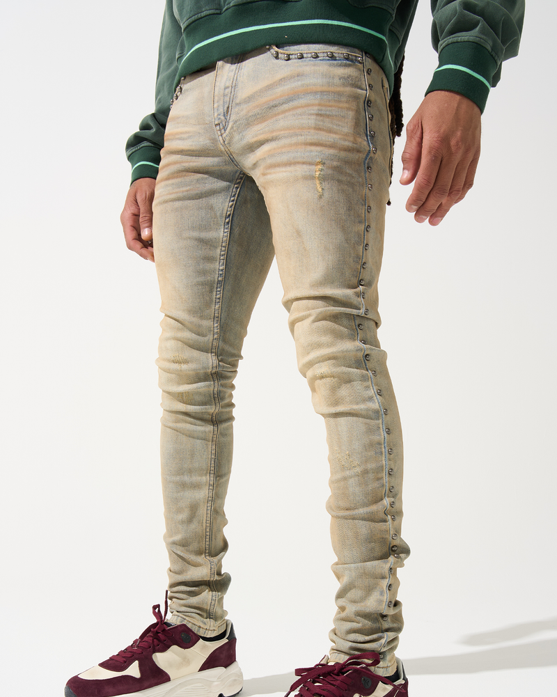 Person wearing beige jeans and maroon sneakers on a white background