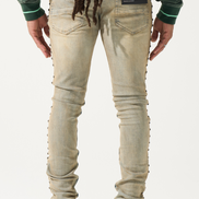 Person wearing beige jeans with decorative elements on a white background