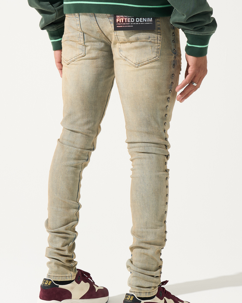 Person wearing beige jeans and maroon sneakers on a white background