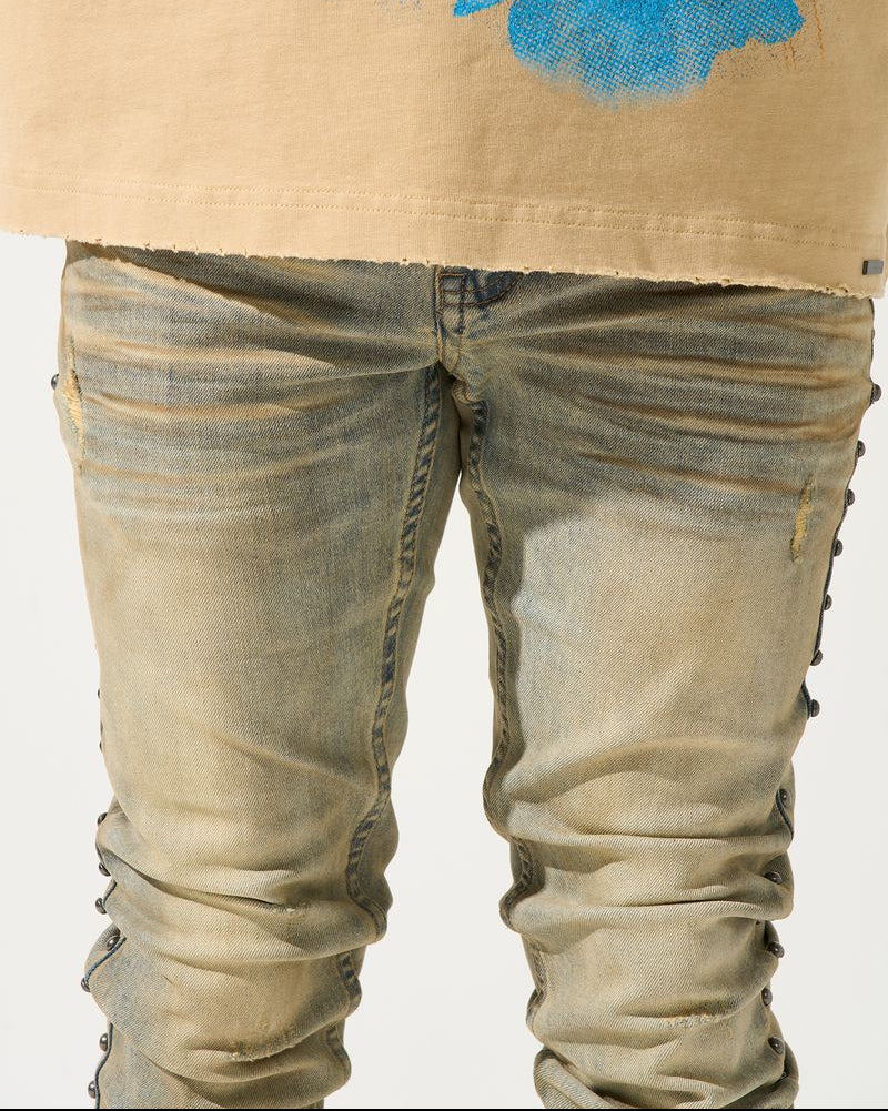Beige jacket with blue abstract design and distressed jeans on a white background