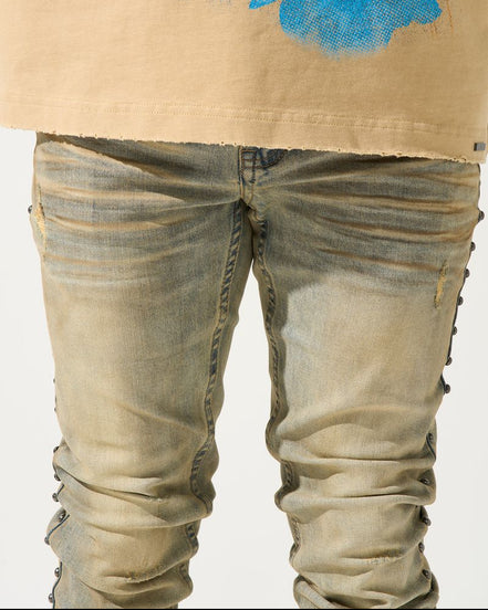 Beige jacket with blue abstract design and distressed jeans on a white background
