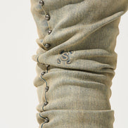 Close-up of beige denim pants with button details on a white background