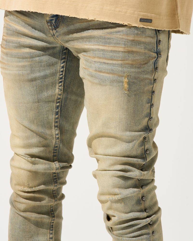 Close-up of beige jeans with a plain background