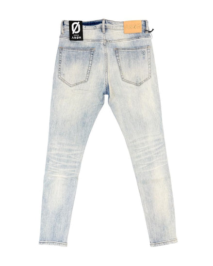 Back view of light-wash denim skinny jeans with a black and white brand patch on the right waistband and a tan leather patch on the left waistband, shown flat on a white background.