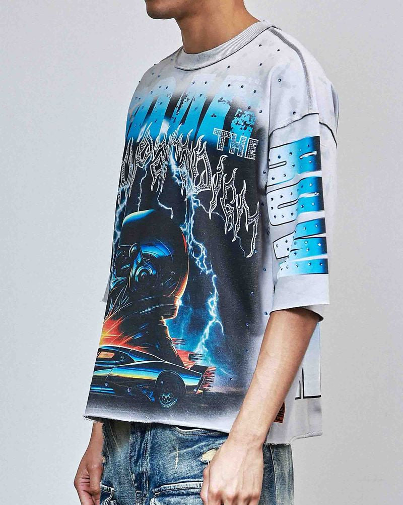 Person wearing a graphic t-shirt with a design of a person in a helmet and car, on a plain background.