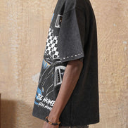 Person wearing a black graphic t-shirt and beige cap against a textured beige wall.