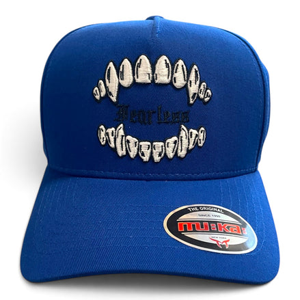 A royal blue snapback cap featuring embroidered white teeth and black text reading 'Fearless Crocodile' on the front, with a circular 'MUKAI' sticker on the brim.