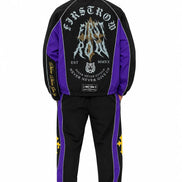 A man shown from the back wearing a black and purple track jacket and matching track pants with large graphic prints and white sneakers, photographed against a plain white background.