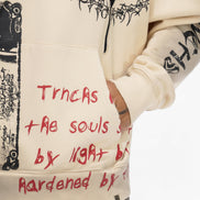 Beige hoodie with black and red text, worn by a person.