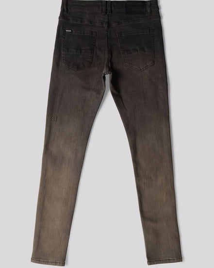 Back view of a pair of slim-fit jeans in a washed charcoal gray color, showing the back pockets and a subtle distressed detail on one leg, set against a solid gray background.
