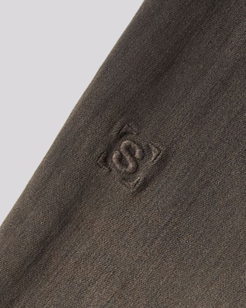Close-up of a dark brown textured knit fabric with a tonal embroidered logo featuring an interlocking 'S' inside a square.