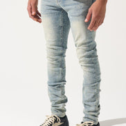 Person wearing light blue jeans and black sneakers on a white background