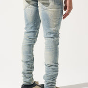 Person wearing light blue distressed jeans and black sneakers on a white background