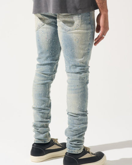 Person wearing light blue distressed jeans and black sneakers on a white background