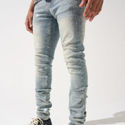 Person wearing light blue distressed jeans and black sneakers on a white background