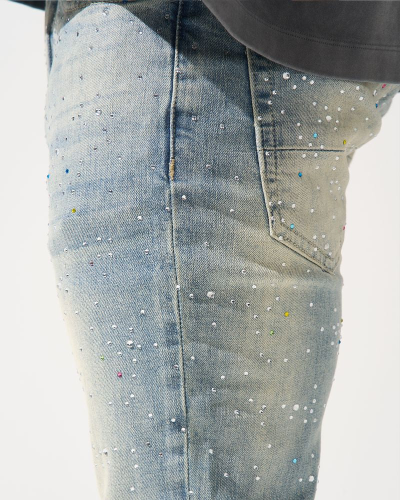 Close-up of light blue jeans with rhinestone embellishments on a white background