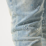 Close-up of light blue jeans with rhinestone embellishments on a white background
