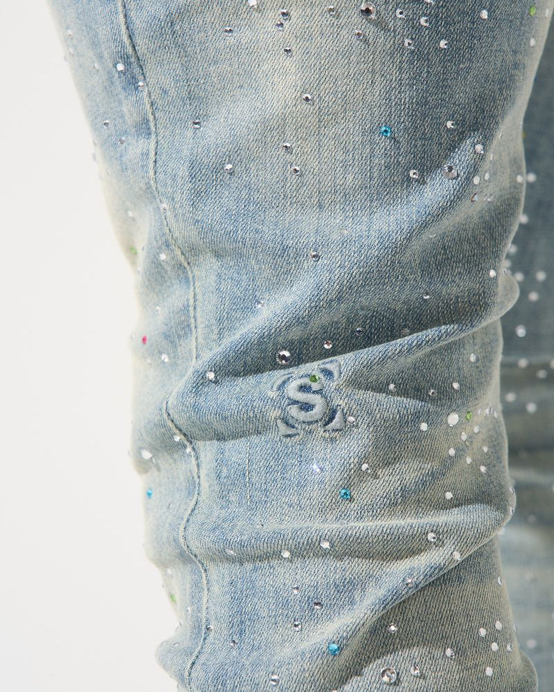 Close-up of light blue jeans with rhinestone embellishments on a white background