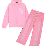 A pink two-piece tracksuit set featuring a zip-up hooded jacket and matching jogger pants. The jacket has a white outlined 'FS' logo on the left chest and silver-tone snap details along the sleeves and hem.
