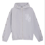 A light gray hooded windbreaker jacket with a white 'FS' monogram logo on the left chest, displayed flat against a white background.