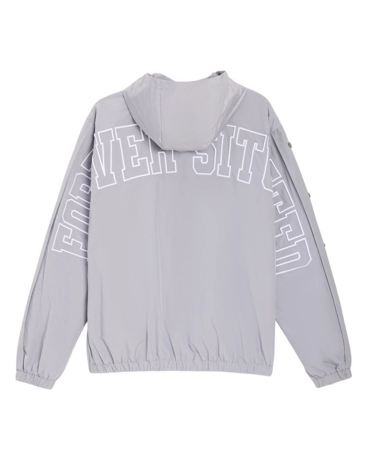 A light gray hooded windbreaker jacket shown from the back, featuring large white outlined text arched across the upper back and sleeves.