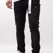 Person wearing black distressed jeans with a visible brand tag on a white background
