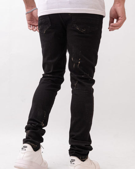 Person wearing black distressed jeans and white sneakers on a white background