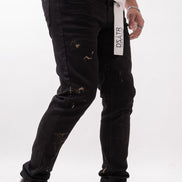 Person wearing black distressed jeans with a visible brand label on a white background