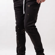 Person wearing black distressed jeans and white sneakers on a white background