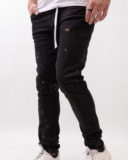 Person wearing black distressed jeans and white sneakers on a white background