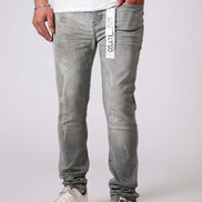 Person wearing gray distressed jeans with a visible brand label on a white background