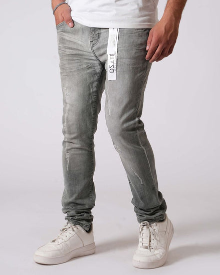 Person wearing gray jeans and white sneakers on a plain background
