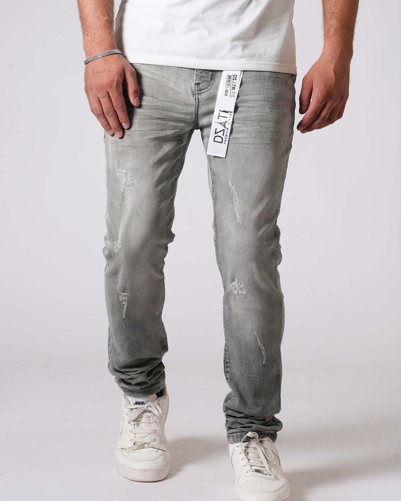 Person wearing light gray distressed jeans with a white label on a plain background