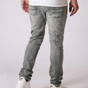 Person wearing gray jeans and white sneakers on a plain background