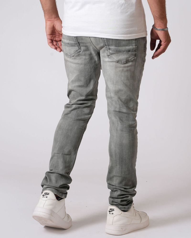 Person wearing gray jeans and white sneakers on a plain background
