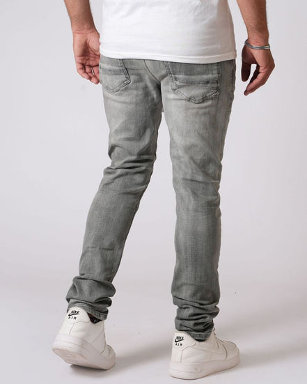 Person wearing gray jeans and white sneakers on a plain background