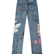 Light blue denim jeans shown from the back, featuring various surreal and graphic prints including a white angel wing, a globe, hand sketches, and pink lips, on a plain white background.