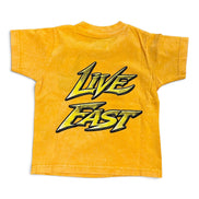 A yellow short-sleeve t-shirt with a faded texture, featuring a large 'LIVE FAST' graphic printed on the front in a stylized black and yellow font, set against a plain white background.