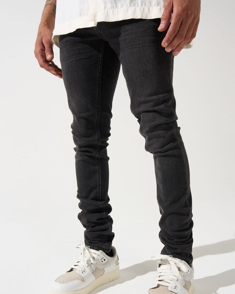 Person wearing black jeans and white sneakers on a white background