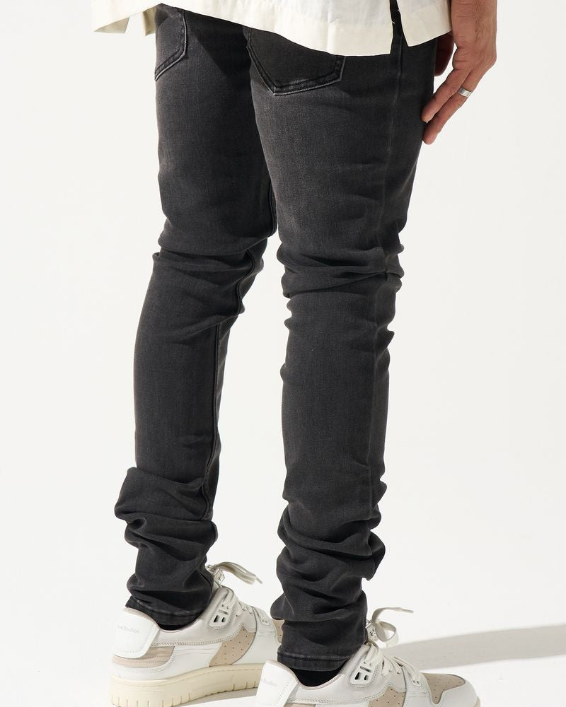 Person wearing black jeans and white sneakers on a white background