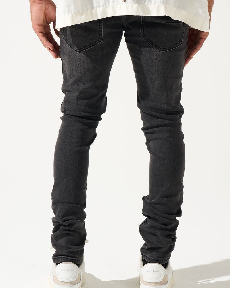 Person wearing black jeans and white sneakers on a plain background